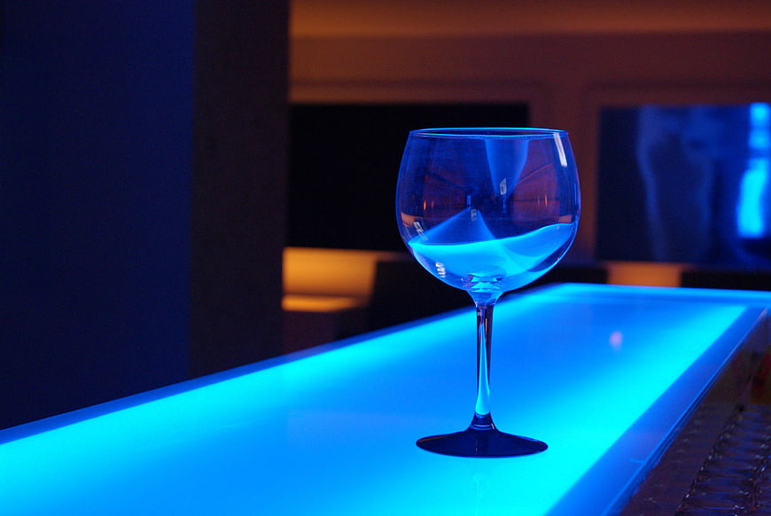Empty wine glass on glowing blue bar counter