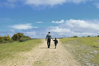 Father and son walking on a gravel path in the countryside
