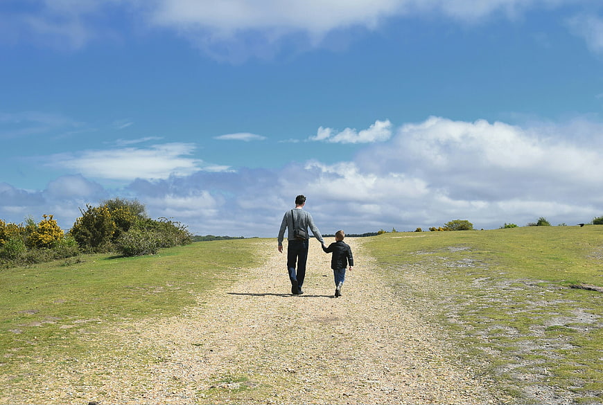 Father and son walking on a gravel path in the countryside