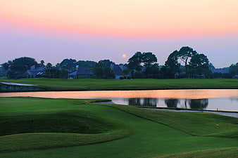 Sunset Over Manicured Golf Course With Water Hazard And Residential Homes