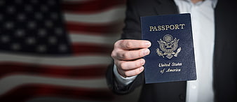 Hand Holding US Passport in Front of American Flag