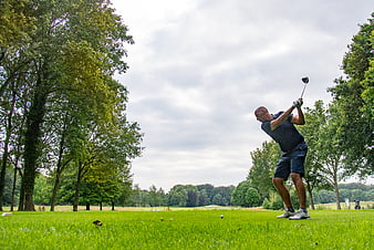 Golfer Swinging Driver on Green Course