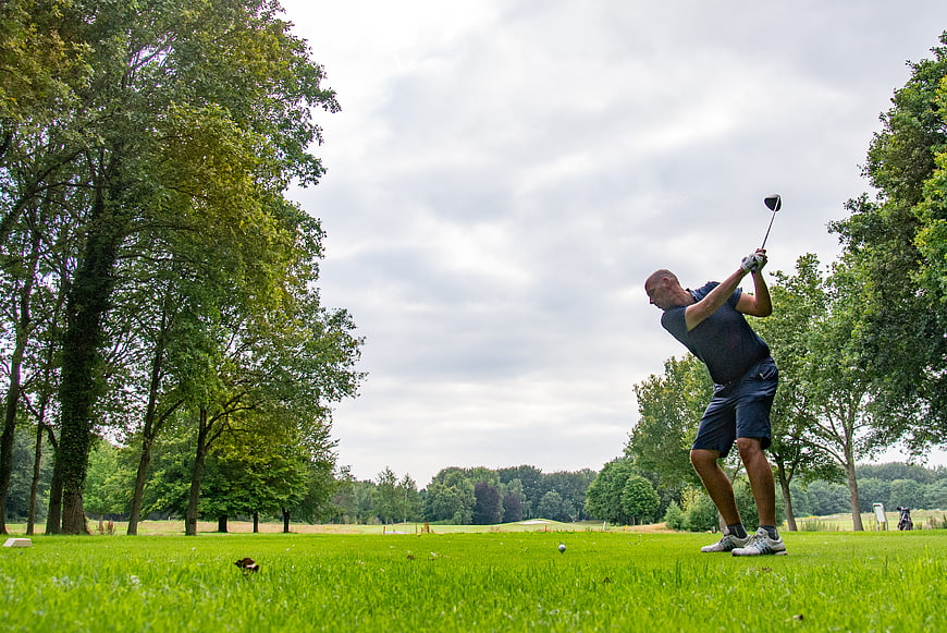 Golfer Swinging Driver on Green Course