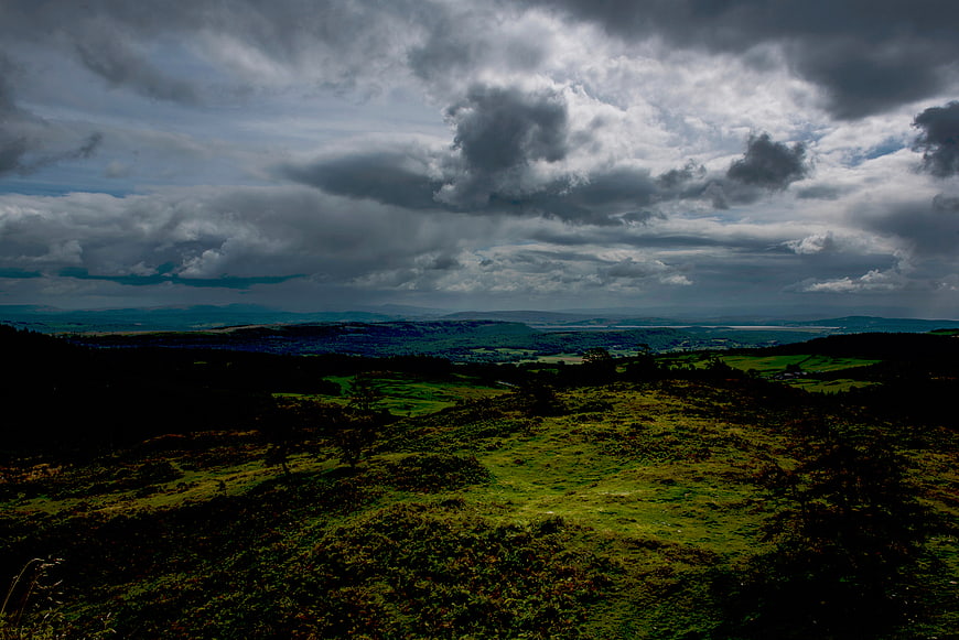 Dramatic moody clouds over rolling green hills landscape