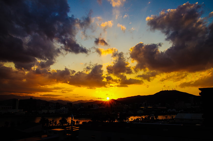 Dramatic sunset over city skyline with mountains and clouds