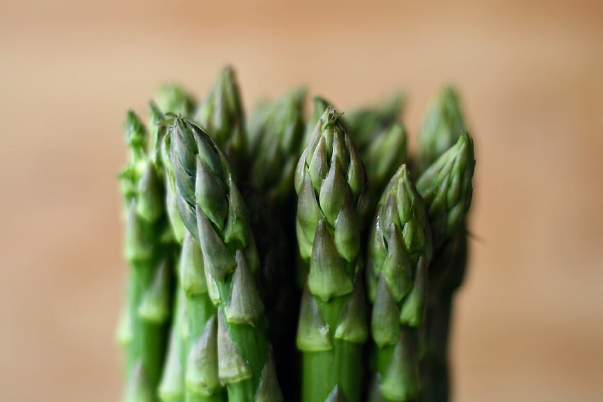Close-up of fresh green asparagus spears on wooden background