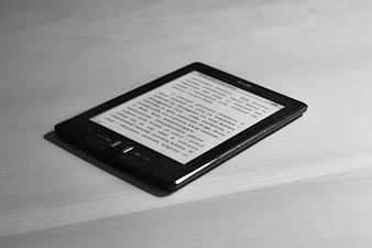 Black E-reader Displaying Text on White Surface