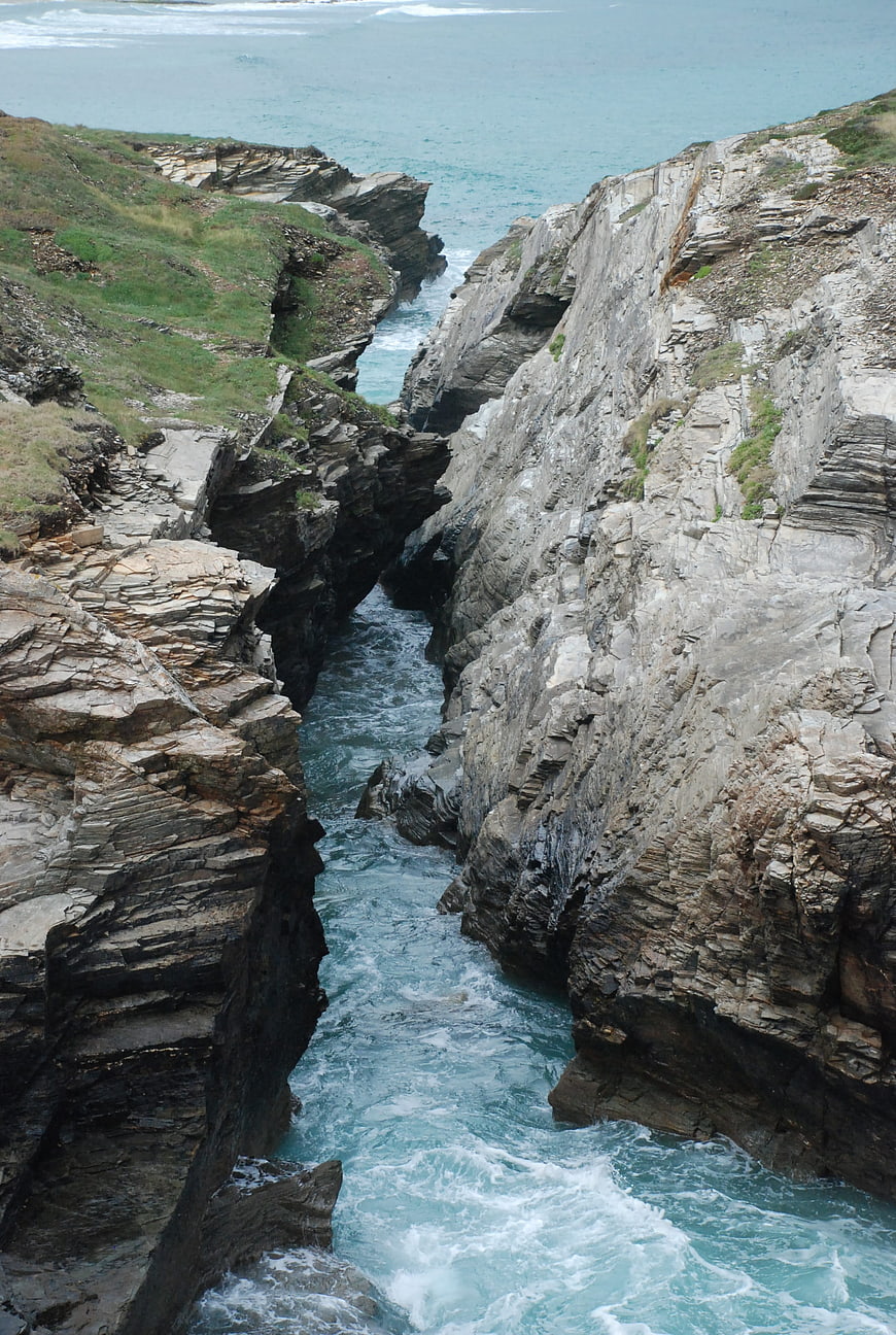Dramatic coastal rock formation with turquoise ocean waves crashing through a narrow gorge