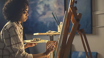 Young woman painting on canvas in art studio