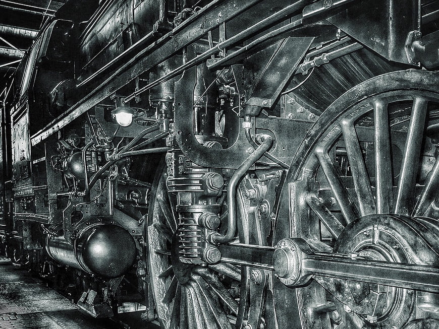 Black and white close-up of vintage steam locomotive wheels and mechanical parts