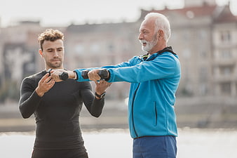 Senior man exercising with dumbbells and personal trainer outdoors