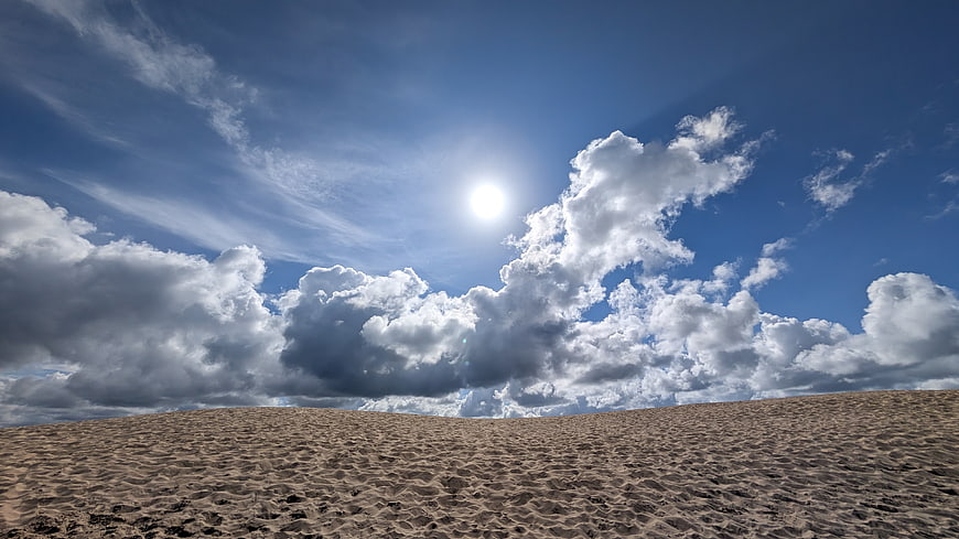 Sandy beach landscape with dramatic cumulus clouds and bright sun