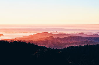 Sunset view of rolling hills and distant city skyline