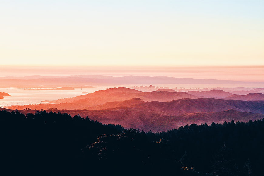 Sunset view of rolling hills and distant city skyline