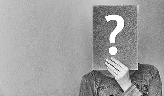 Person holding question mark sign covering face in black and white