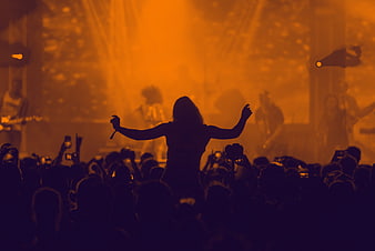 Silhouetted performer with raised arms at a live concert