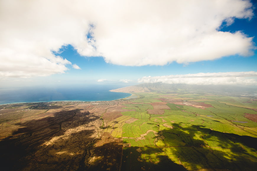 Aerial View of Green Fields, Ocean Coastline, and Cloud Shadows