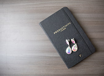 Black productivity planner with iridescent earrings on wood