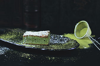 Green Pistachio Cake Slice On Dark Plate With Powder