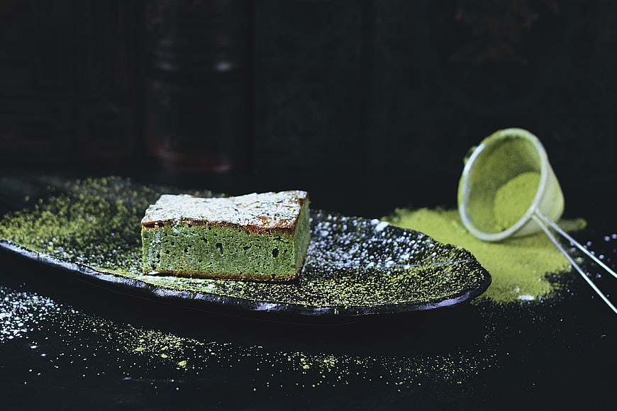 Green Pistachio Cake Slice On Dark Plate With Powder