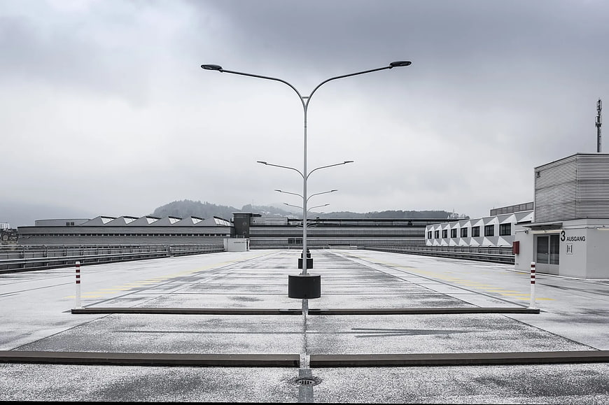 Symmetrical view of empty rooftop parking lot with street lamps