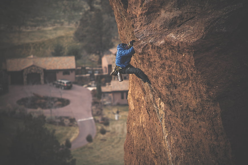 Rock Climber Scaling Red Sandstone Cliff Face