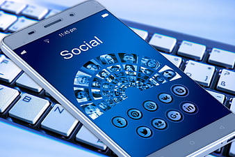 Smartphone displaying social media icons on a laptop keyboard