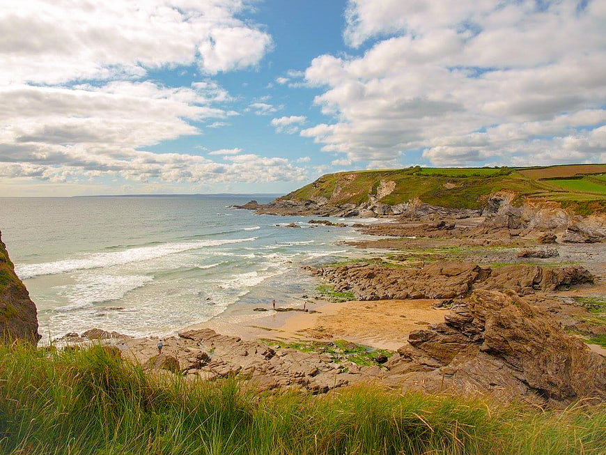 Scenic coastal landscape with rocky cliffs, sandy beach, and blue sky