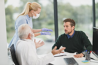 Upset male patient arguing with doctor and nurse in clinic