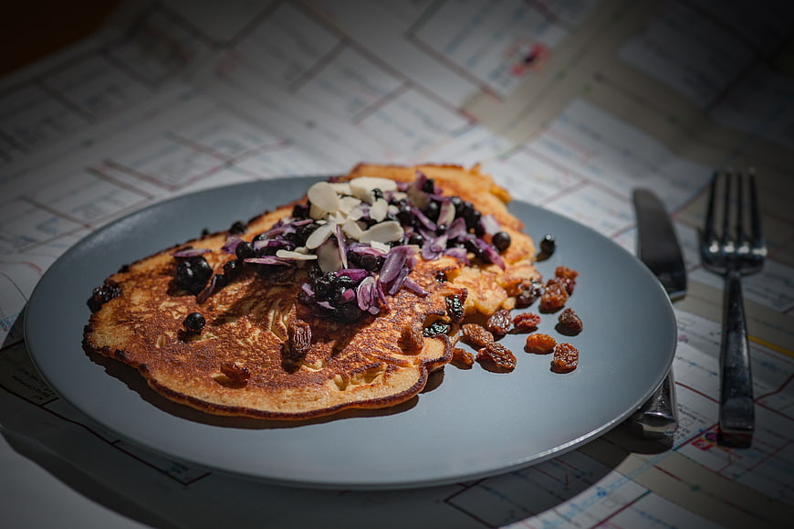 Golden pancakes with raisins and almonds on a gray plate