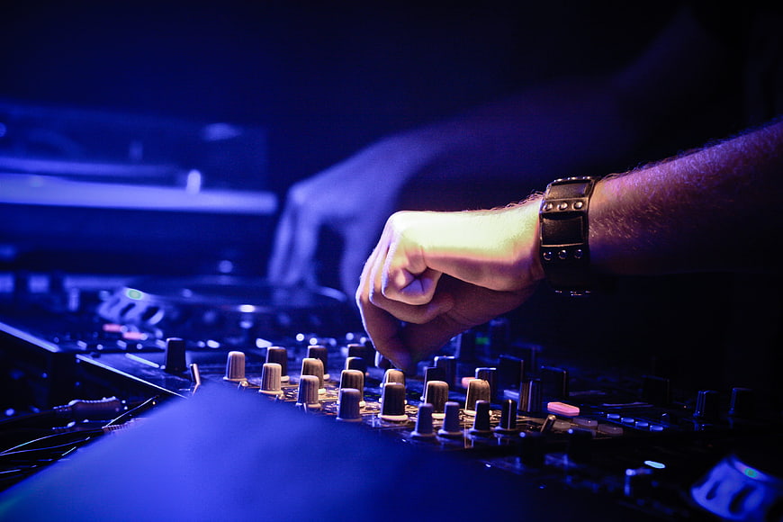 DJ Hand Adjusting Mixer Knobs in Blue Club Lighting