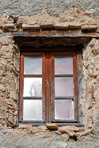 Old wooden window in weathered stone wall