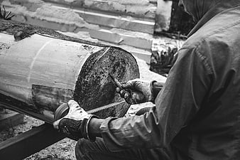 Carpenter measuring a large timber log with tape measure