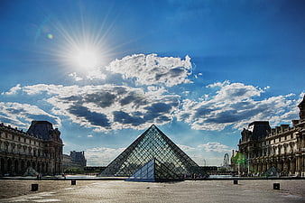 Louvre Pyramid in Paris under bright blue sky