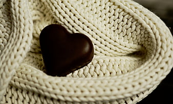 Chocolate heart nestled in cozy cream knit fabric close-up