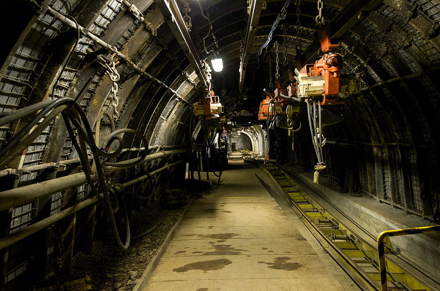 Underground mine tunnel with heavy machinery and tracks