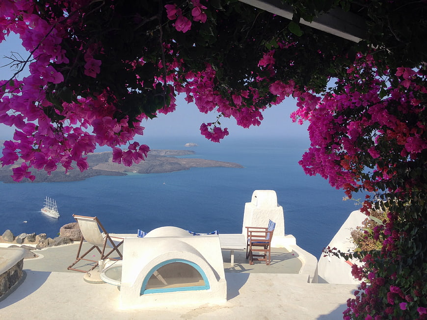 Santorini terrace with vibrant pink bougainvillea framing a blue sea view