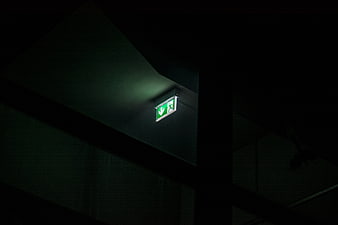 Illuminated green emergency exit sign in dark industrial interior
