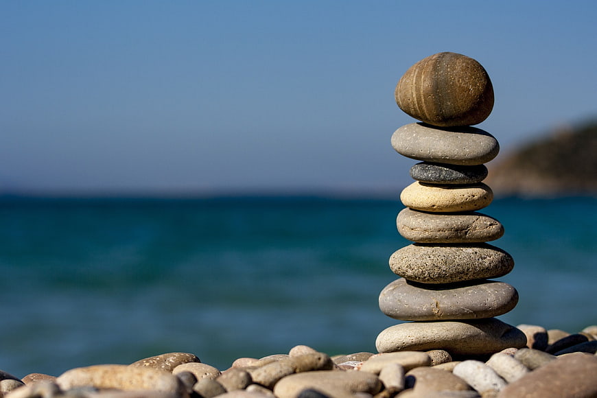 Stacked Beach Stones on Pebble Shore with Ocean Background