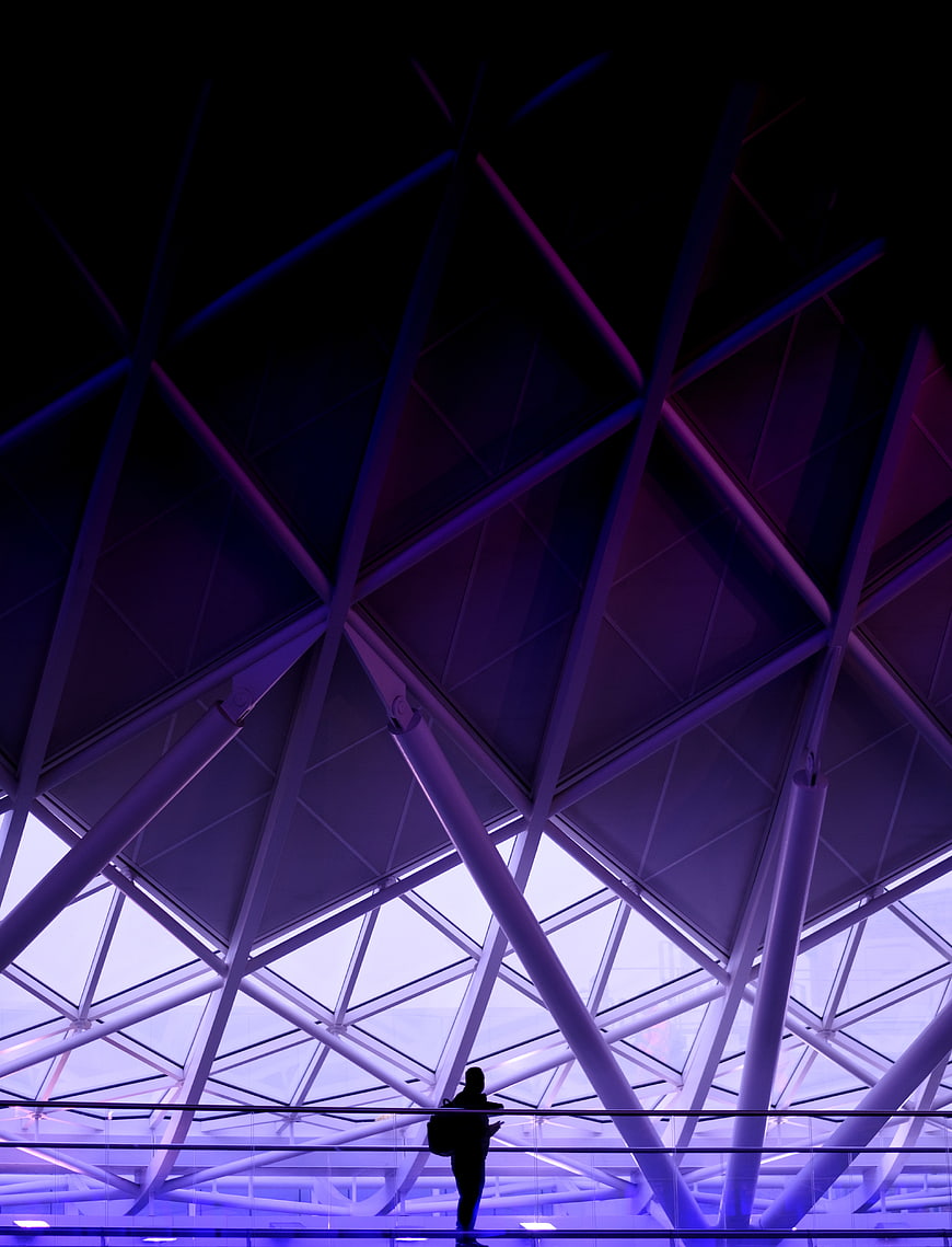 Silhouette of traveler under purple geometric airport ceiling