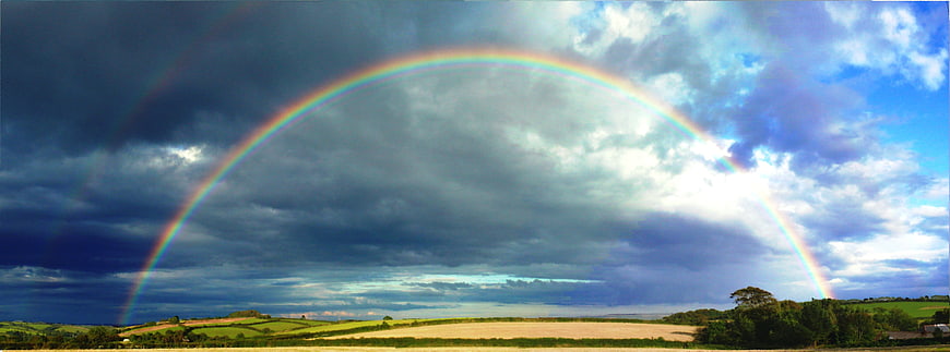 Double rainbow arching over green countryside landscape
