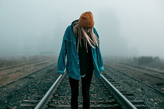 Melancholic Woman Walking on Foggy Railway Tracks