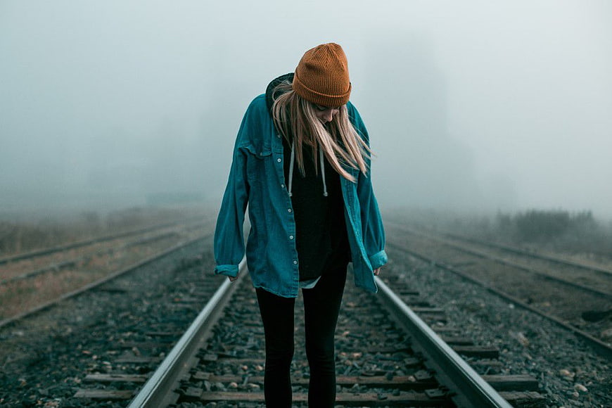 Melancholic Woman Walking on Foggy Railway Tracks