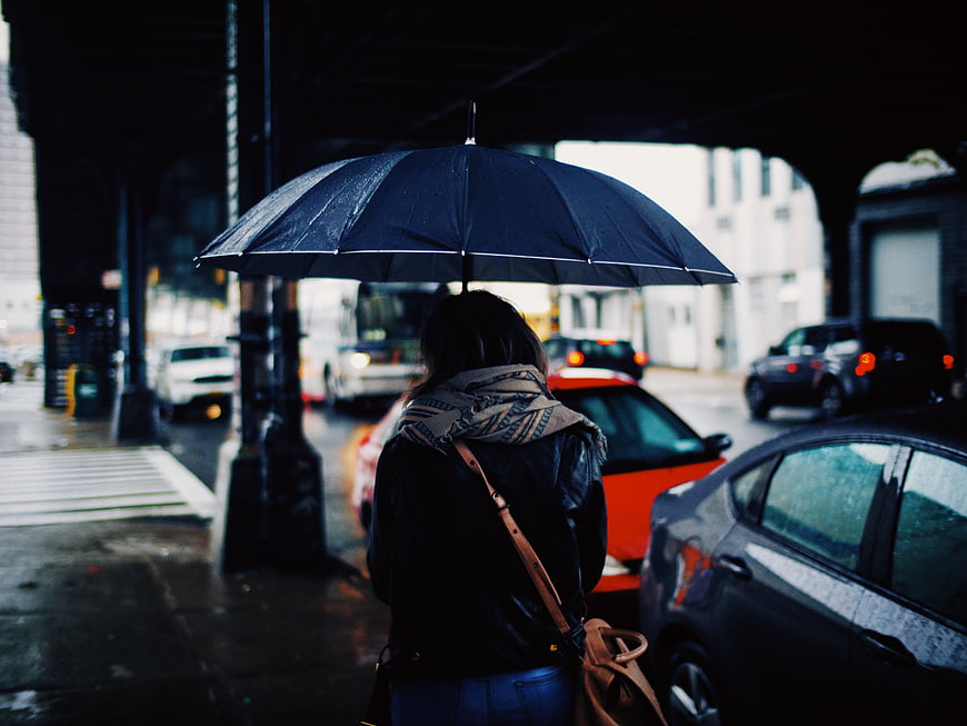 Woman with Umbrella Waiting for Taxi in Rainy City