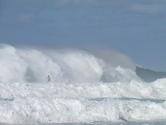 Surfer riding massive ocean wave with white spray