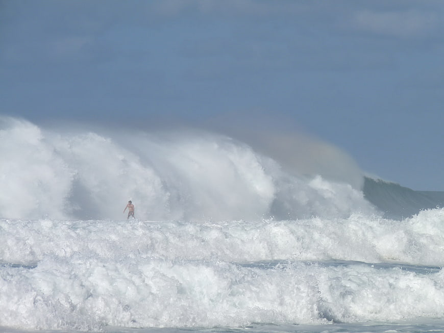 Surfer riding massive ocean wave with white spray