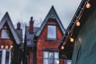 String lights on green roof with blurred brick houses