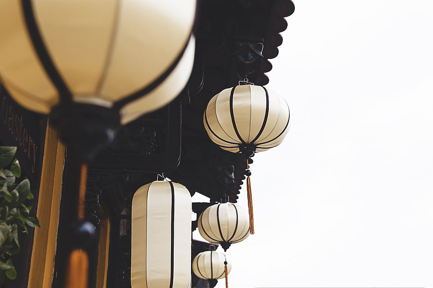 Traditional Asian Paper Lanterns Hanging from Wooden Eaves