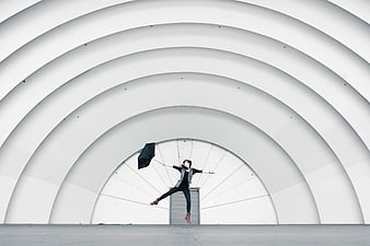 Woman Leaping With Umbrella Under White Architectural Arches