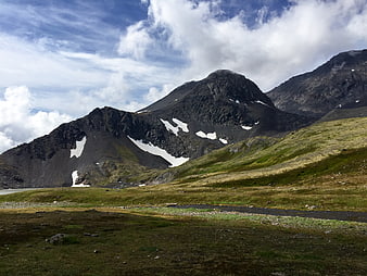 Scenic mountain landscape with snow patches and green meadow